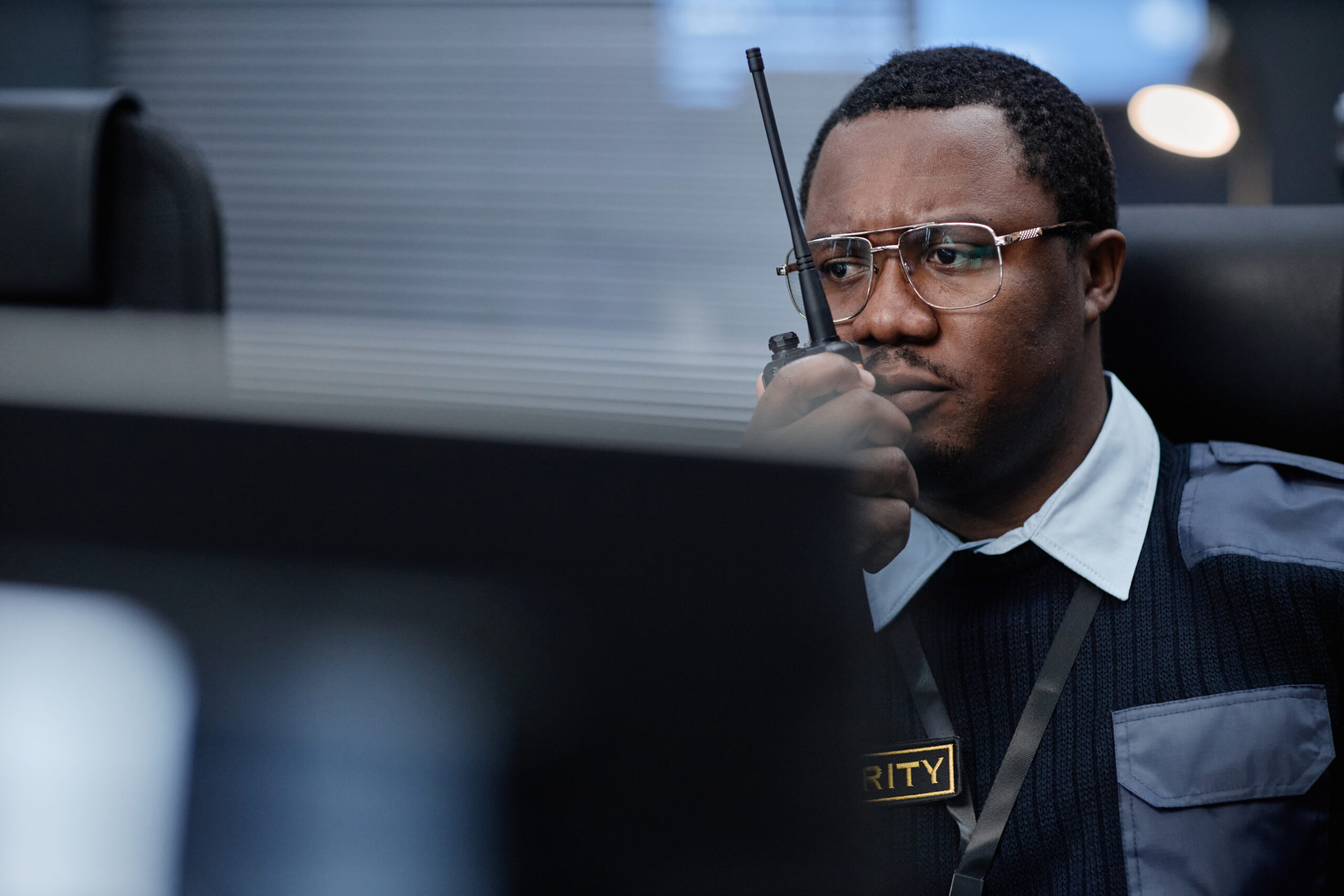 Middle Aged Black Man Monitoring Security Systems While Using Walkie Talkie